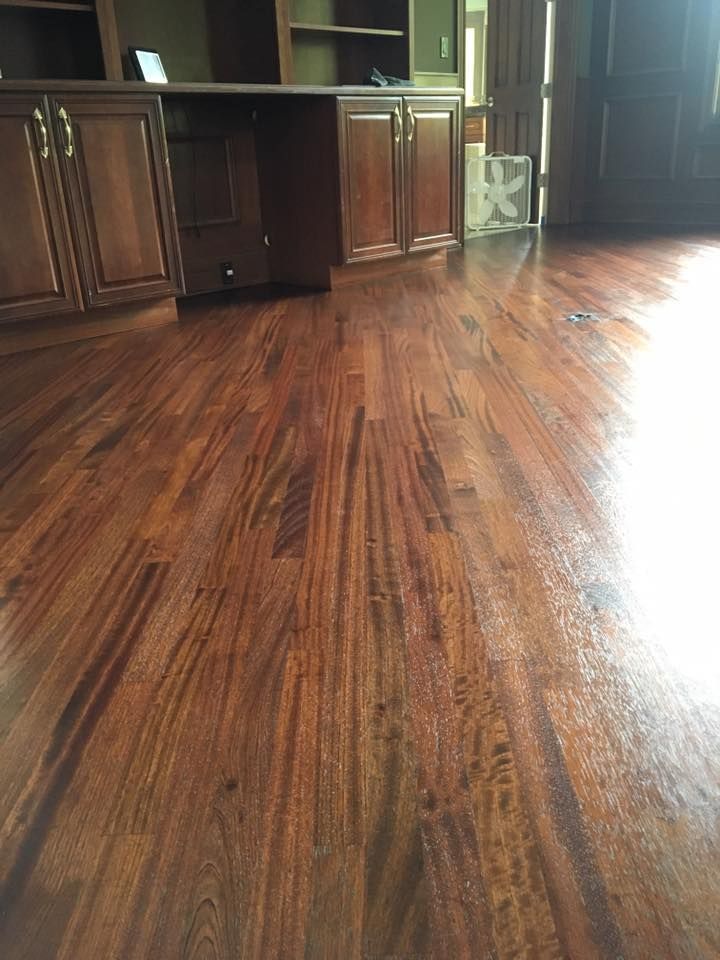 A wooden floor in a living room with cabinets and a fan.