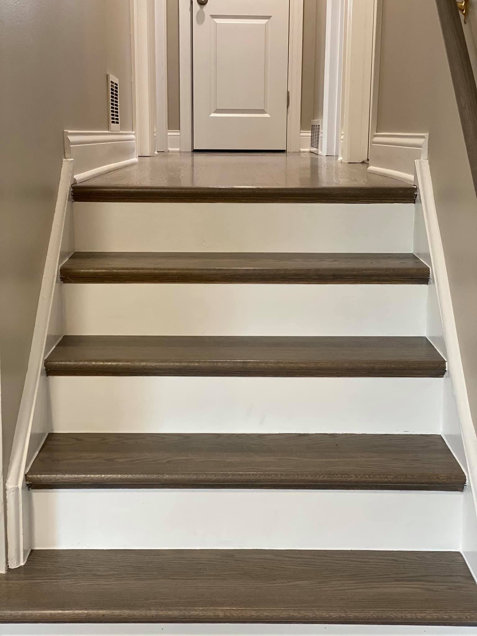 A set of white stairs with wooden steps leading up to a door.
