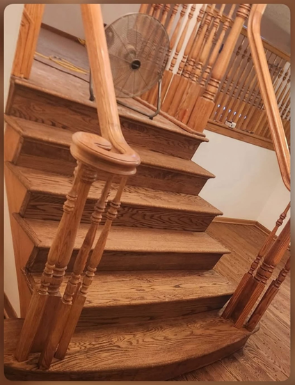 Wooden staircase with curved handrail and spindle railing.