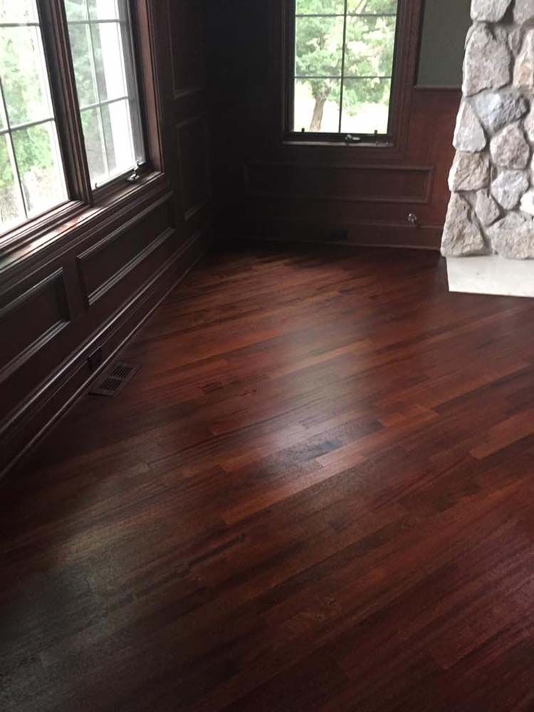 A room with hardwood floors and a stone fireplace.