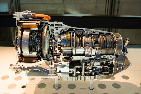 Cutaway view of a large metallic engine or turbine displayed on a stand, with exposed internal components
