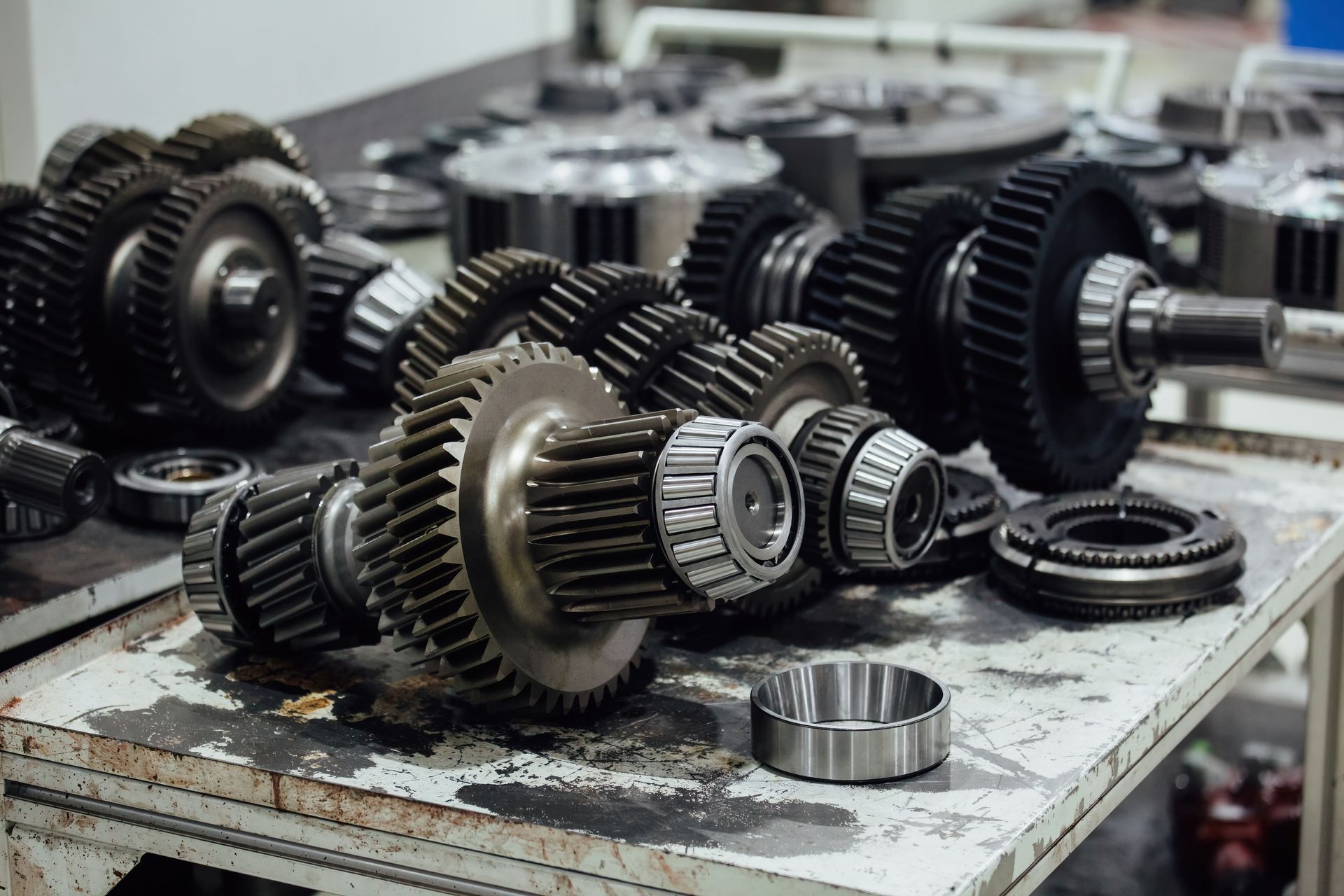 Gears and metal transmission parts laid out on a worn workshop table.