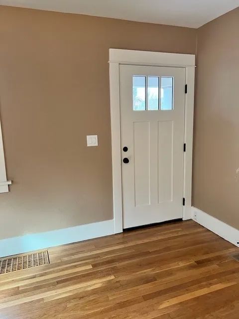 An empty room with hardwood floors and a white door.