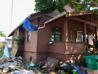 A brick house with a blue tarp hanging from the roof.