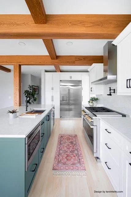 A kitchen with white cabinets, stainless steel appliances, and wooden beams.