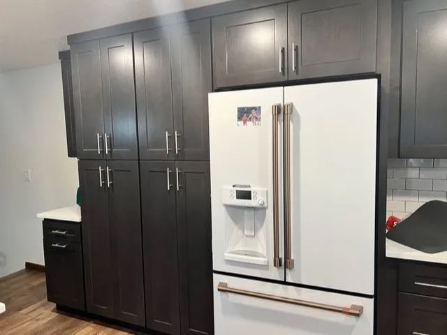 A kitchen with black cabinets and a white refrigerator.