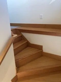 A wooden staircase with a wooden railing in a house.