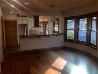 An empty living room with hardwood floors and lots of windows.