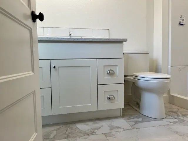 A bathroom with white cabinets and a toilet