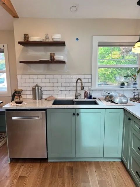 A kitchen with green cabinets and a stainless steel dishwasher