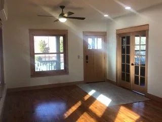 An empty living room with hardwood floors and a ceiling fan.