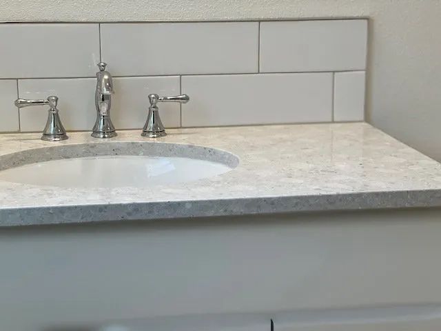 A bathroom sink with a marble counter top and chrome faucets.
