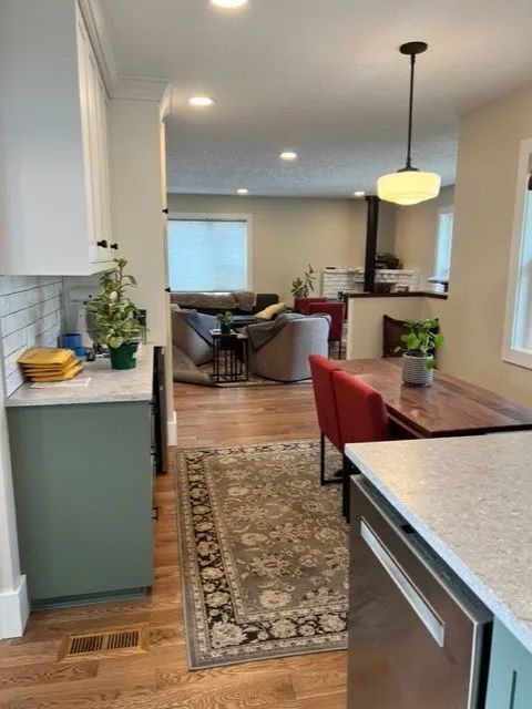 A kitchen with a rug on the floor and a stainless steel dishwasher