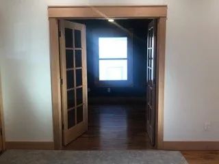 A hallway with a door open and a window in the background.