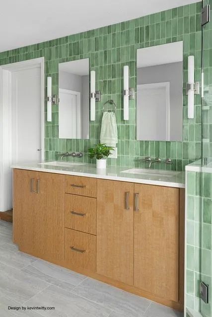 A bathroom with green tiles and two sinks