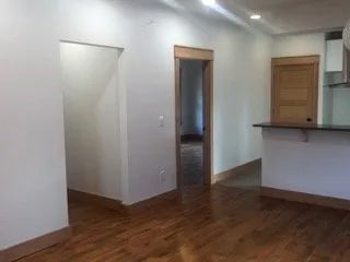 An empty room with hardwood floors and white walls.