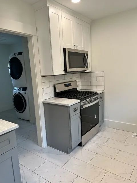 A kitchen with a stove, microwave, washer and dryer.