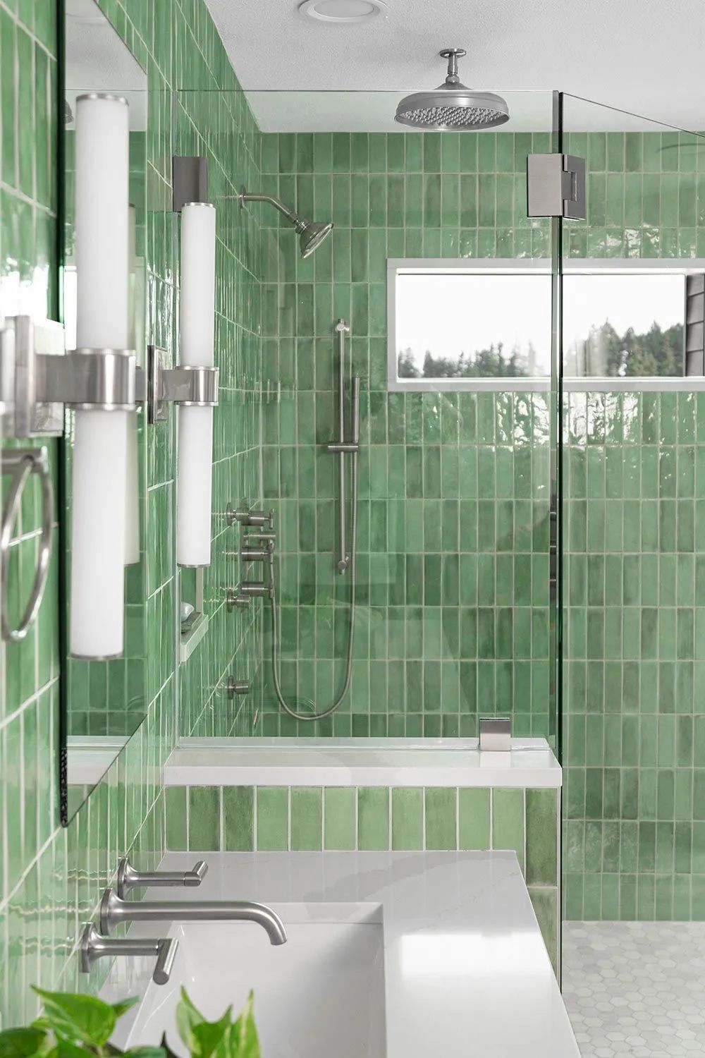 A bathroom with green tiles, a sink, and a shower.