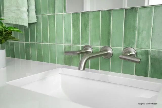 A bathroom sink with green tiles and a faucet.
