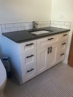 A bathroom vanity with a sink and black counter top.