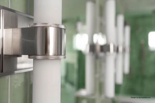 A close up of a stainless steel pipe in a bathroom.