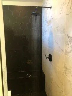 A shower with a black shower head in a bathroom.