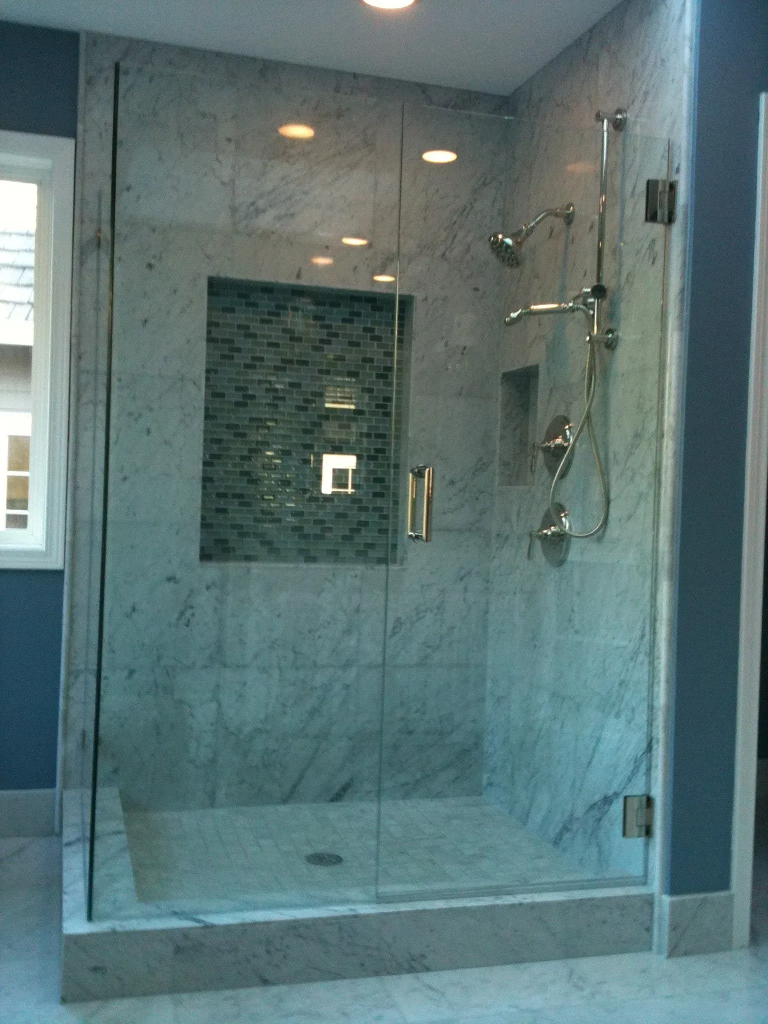 A bathroom with a walk in shower with a glass door