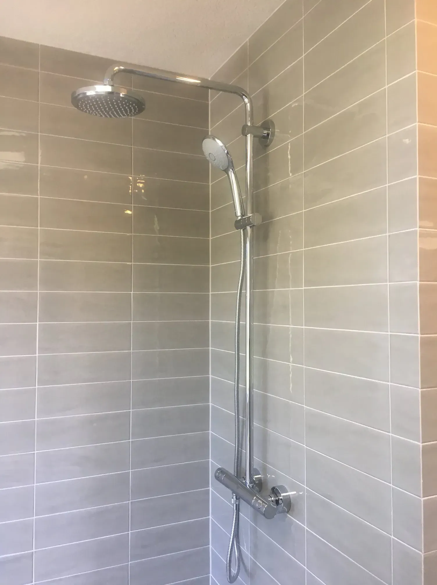 A shower head is hanging from the ceiling in a bathroom.
