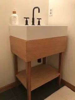 A bathroom sink with a wooden cabinet and a shelf underneath it.