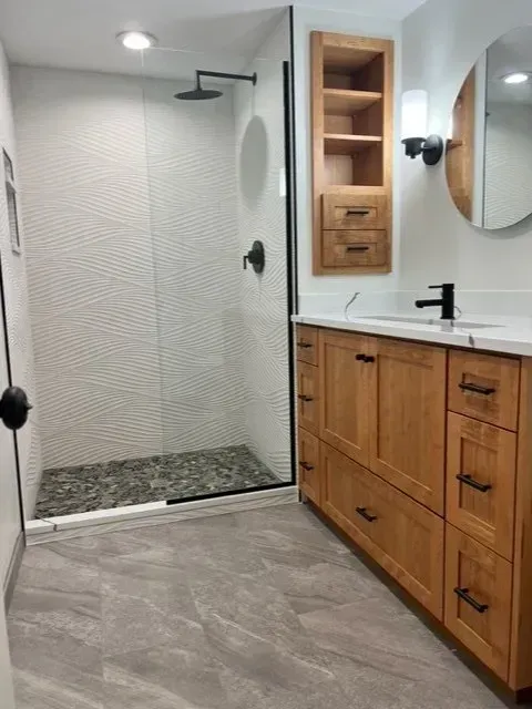 A bathroom with a walk in shower and a sink