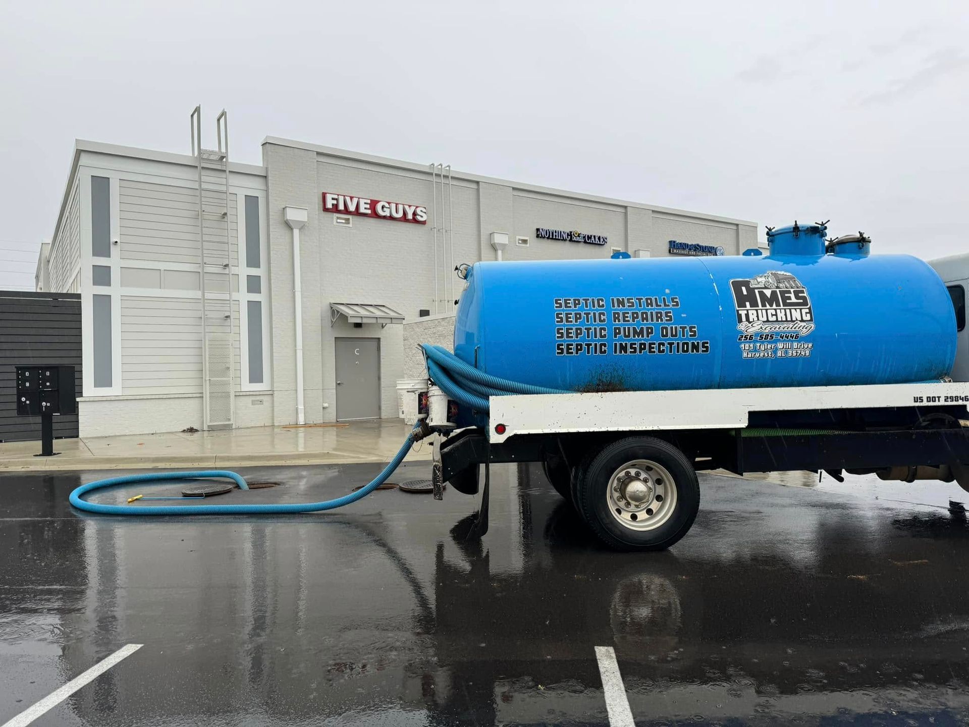 A blue vacuum truck is parked in front of a building.