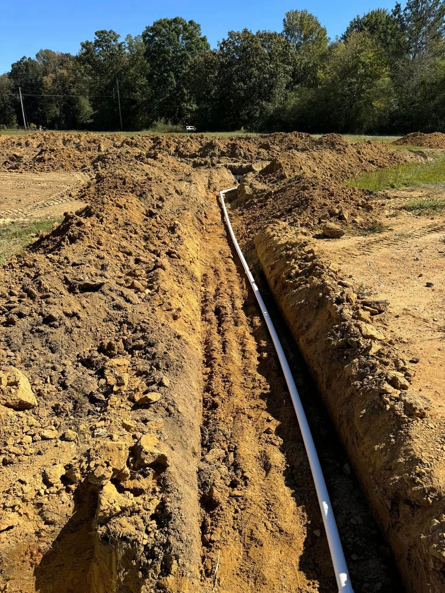A pipe is being installed in the dirt in a field.