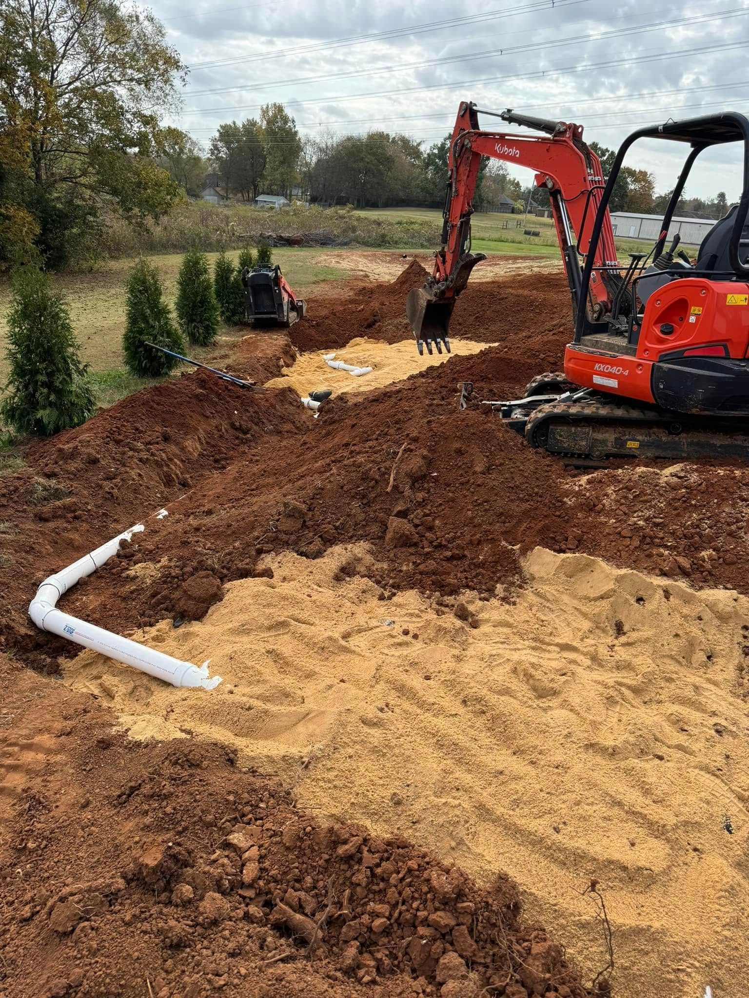 A red excavator is digging a hole in the dirt.