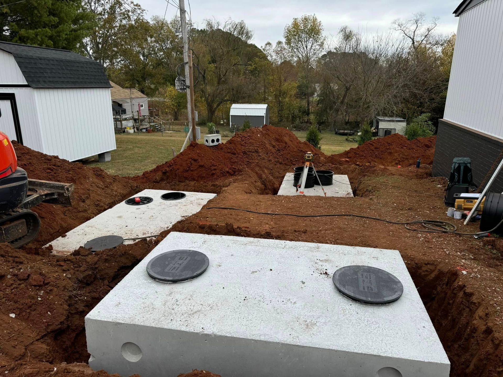 A septic tank is being built in the dirt in front of a house.