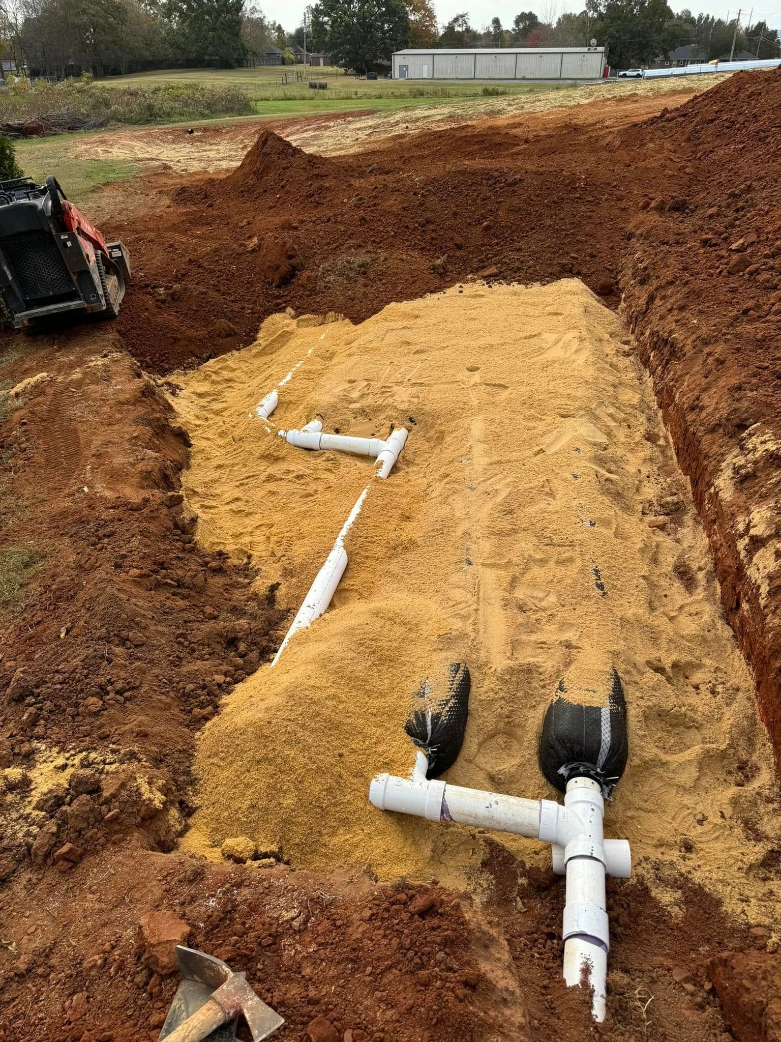 A pile of dirt with pipes in it and a bulldozer in the background.