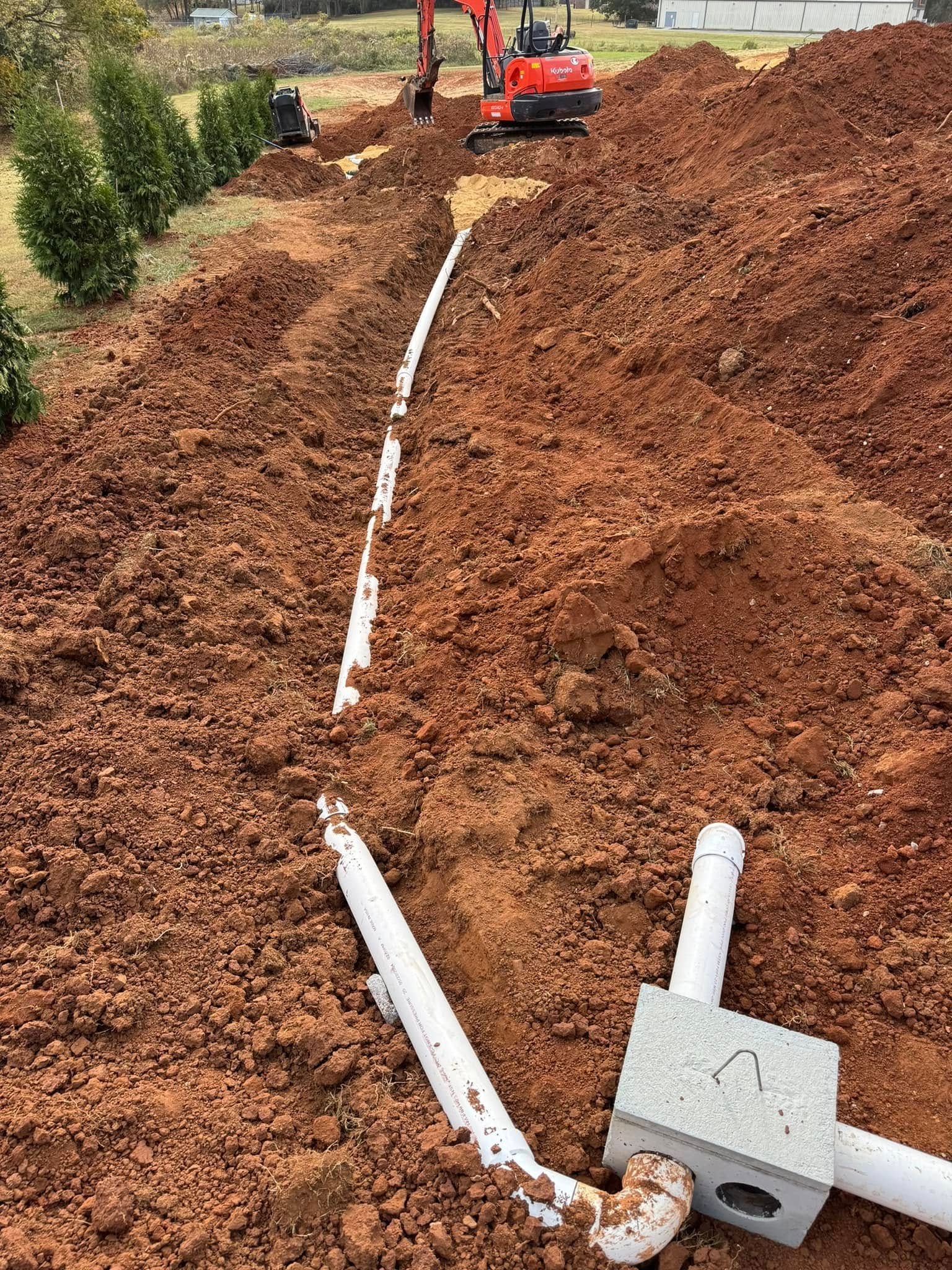 A red excavator is digging a trench in the dirt.