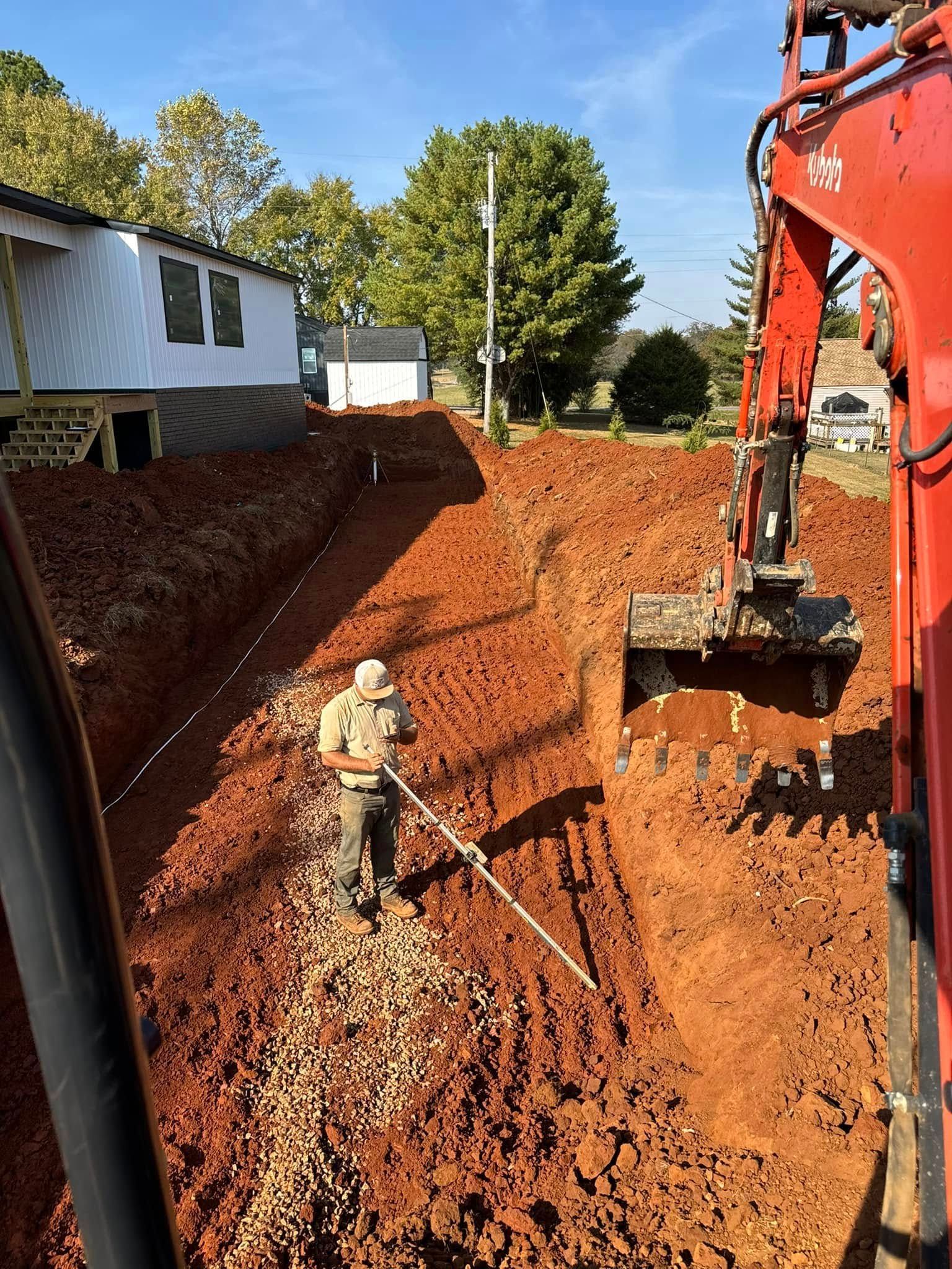 A man is standing in the dirt next to an excavator.