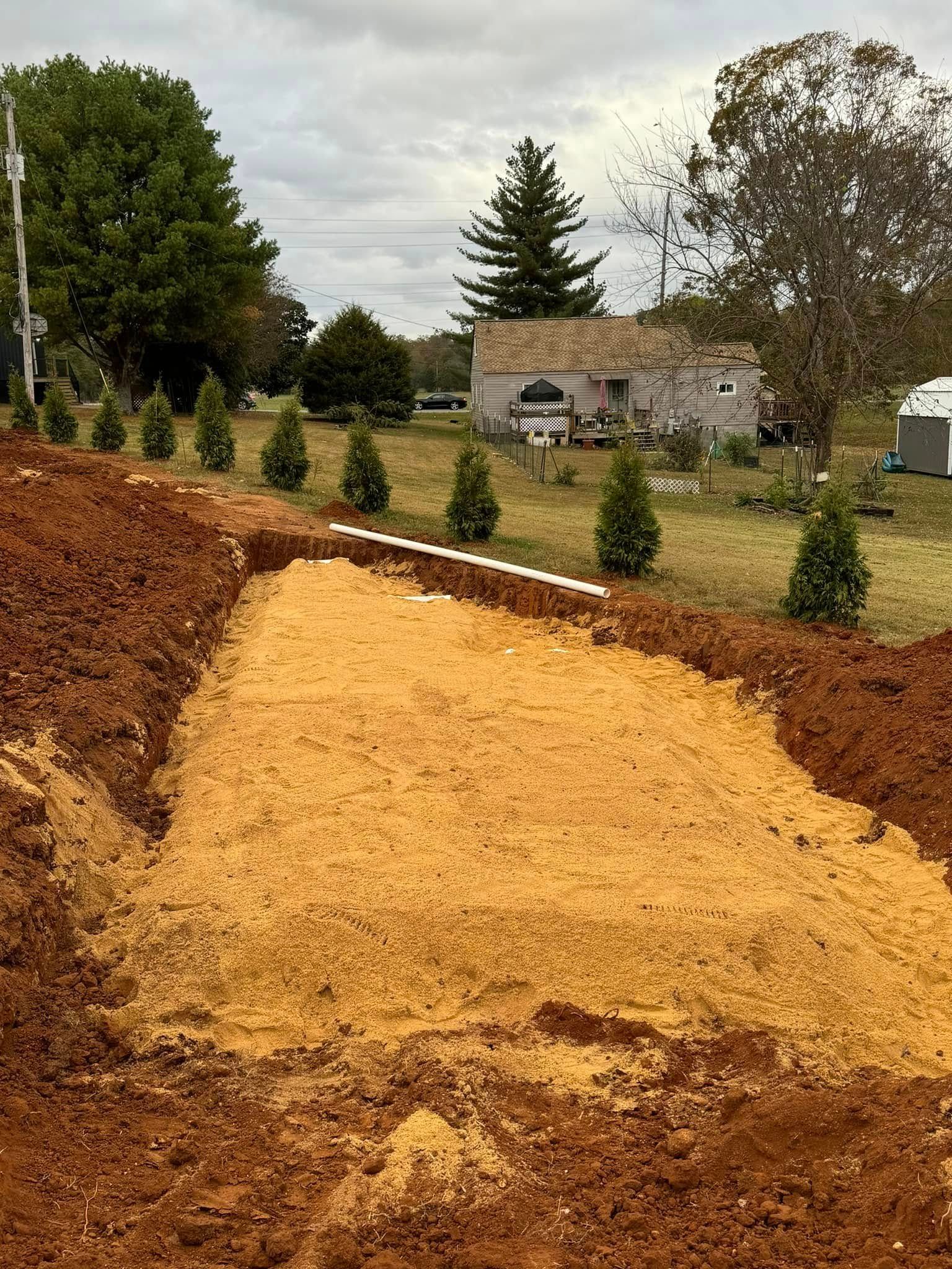 A large pile of dirt is sitting in the middle of a field next to a house.