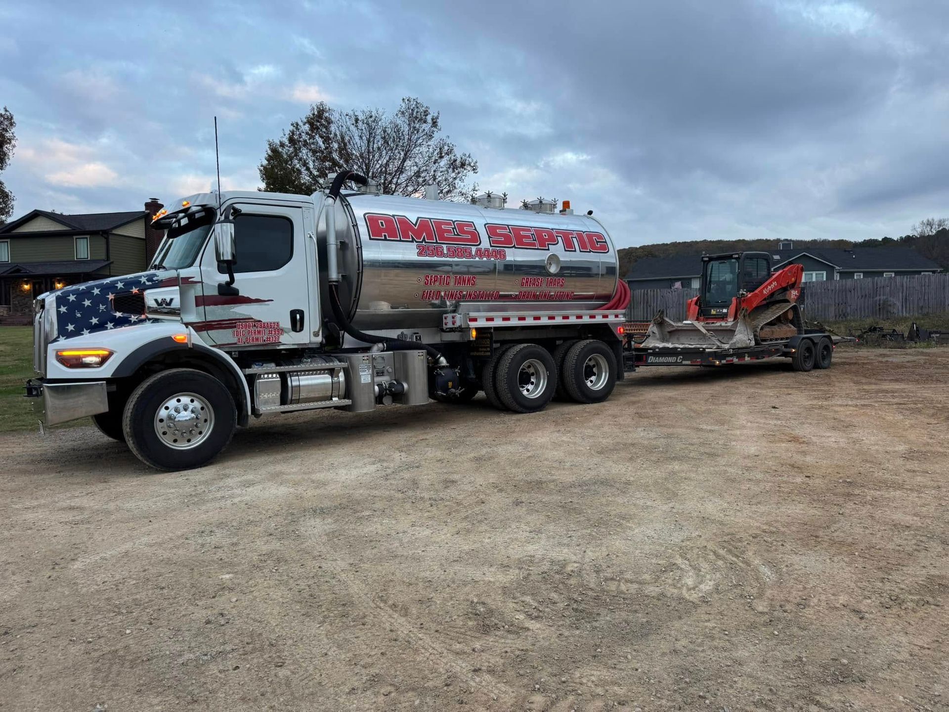 A semi truck with a trailer attached to it is parked in a dirt lot.