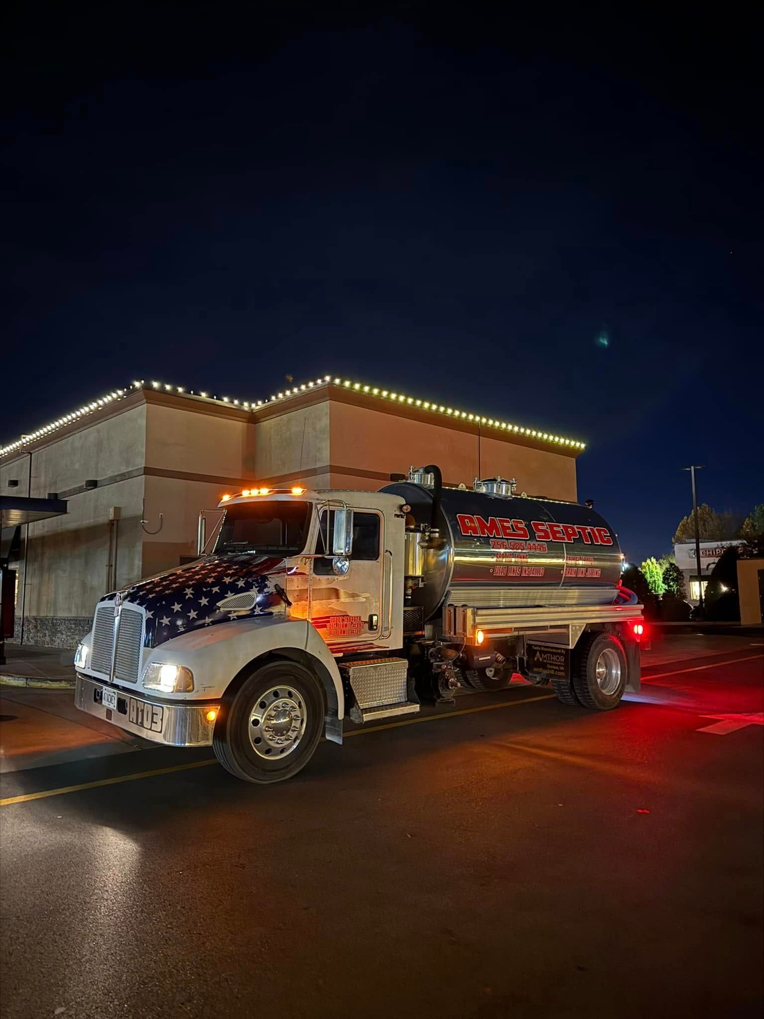 A white semi truck is parked in front of a building at night.