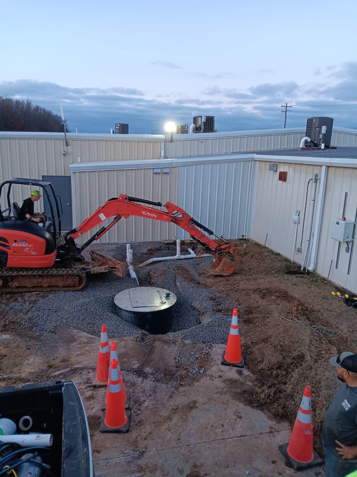 An excavator is digging a hole in the dirt in front of a building.