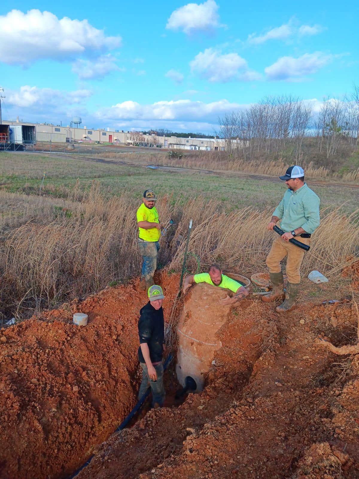 A group of men are digging a hole in the dirt in a field.