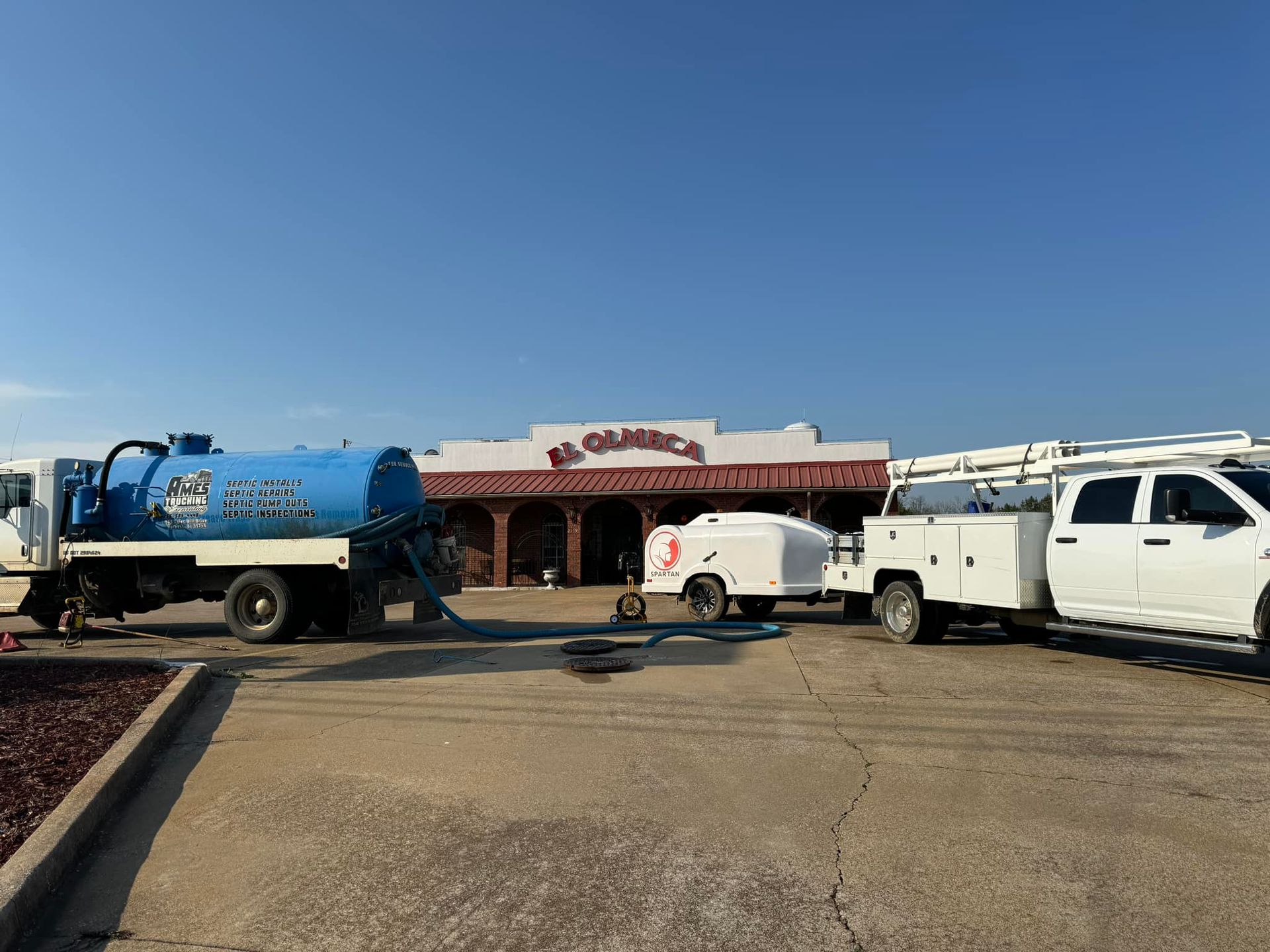 A vacuum truck is parked in front of a building.