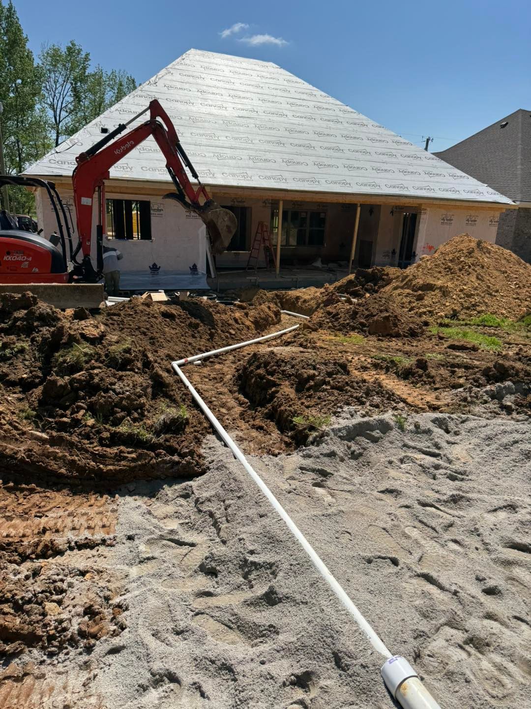 A large pile of dirt is in front of a house under construction.
