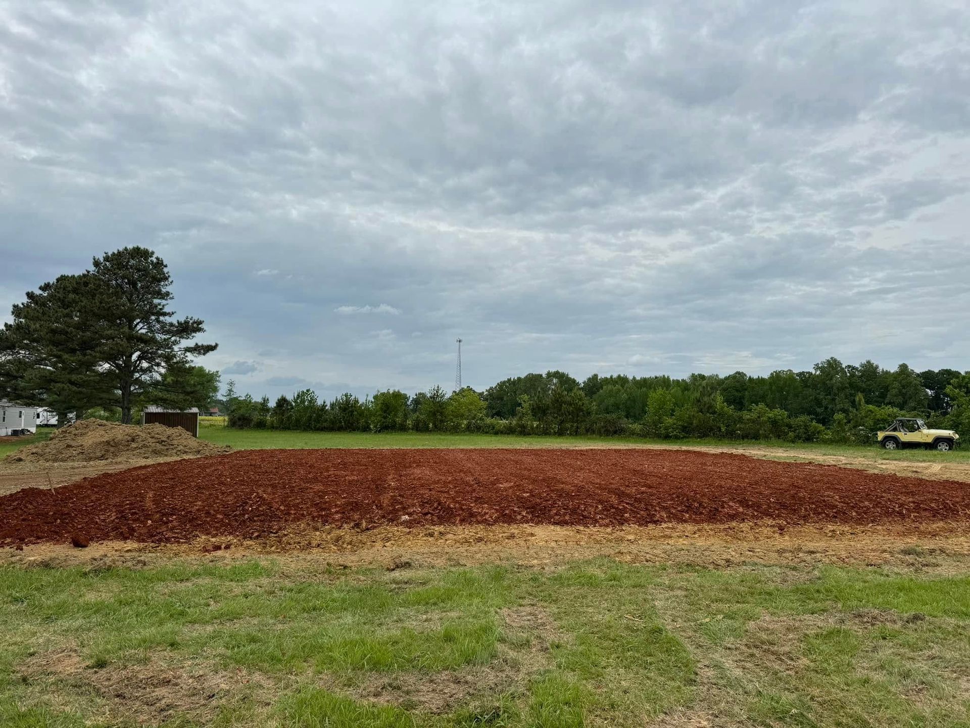 There is a large pile of dirt in the middle of a field.