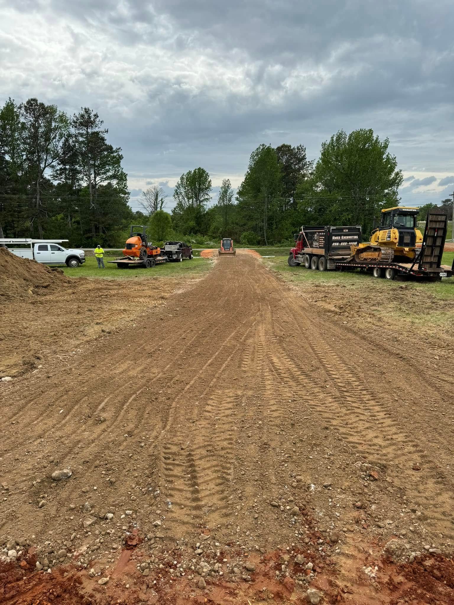 A dirt road with trucks and tractors parked on the side of it.