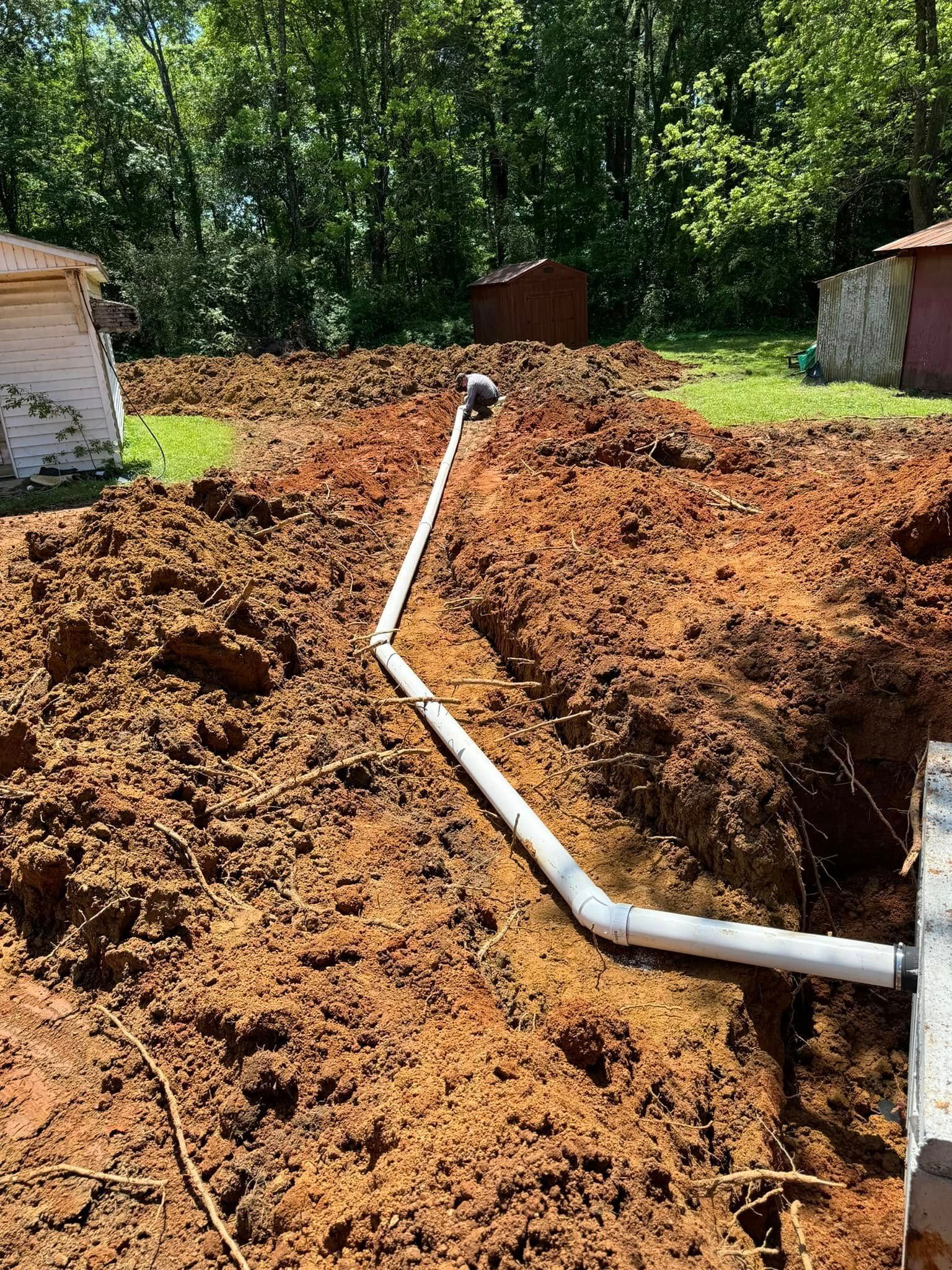 A pipe is being installed in the dirt in a backyard.