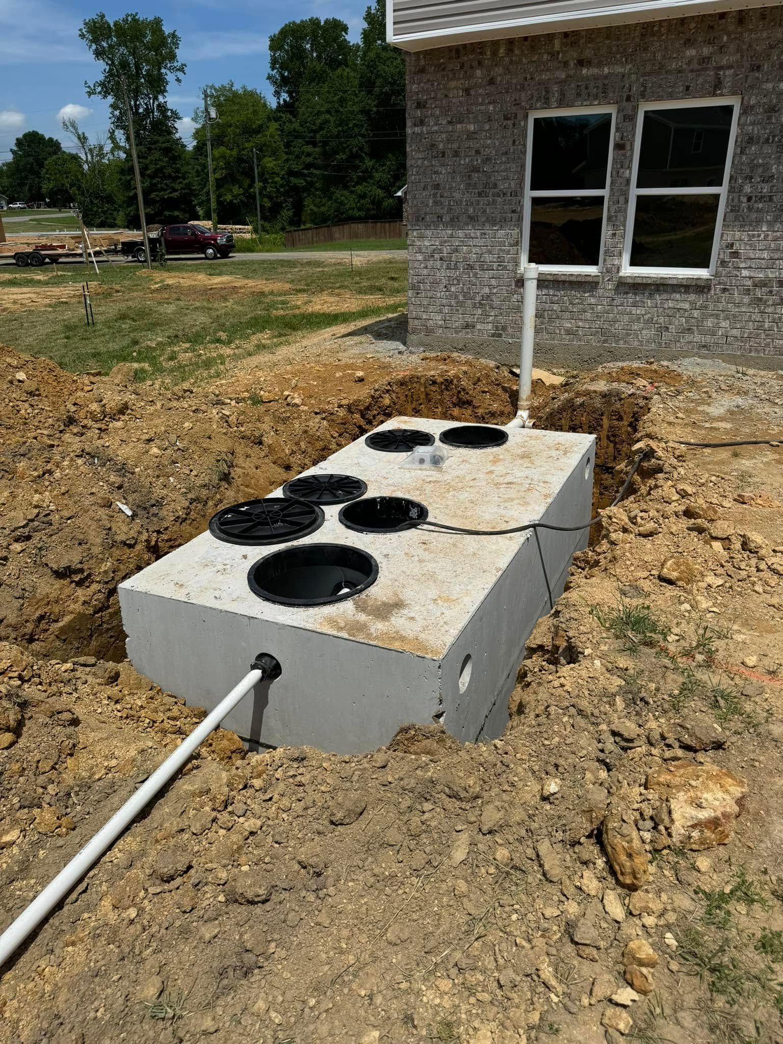 A septic tank is sitting in the dirt in front of a house.