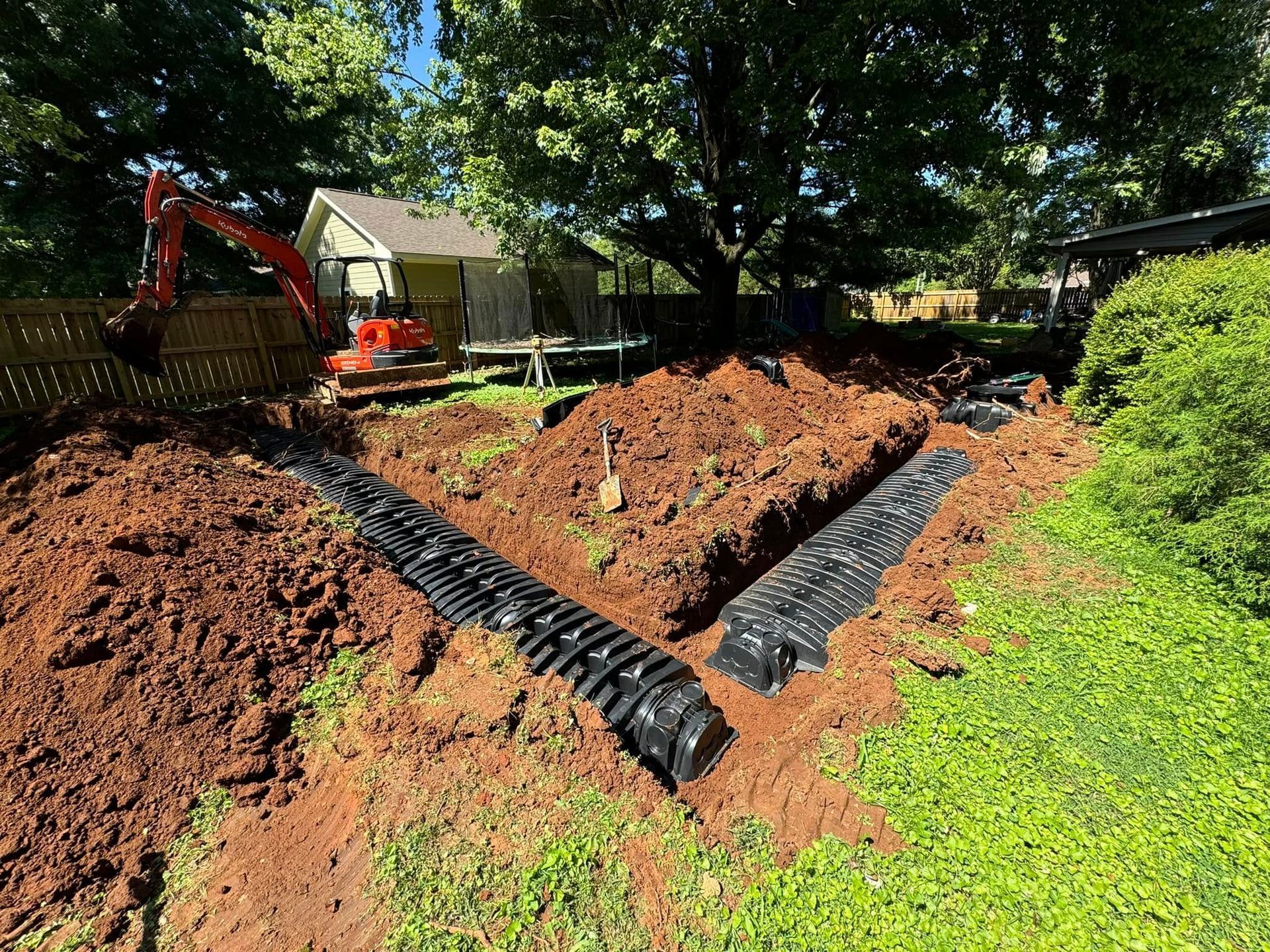 A large pile of dirt is being excavated in the backyard of a house.