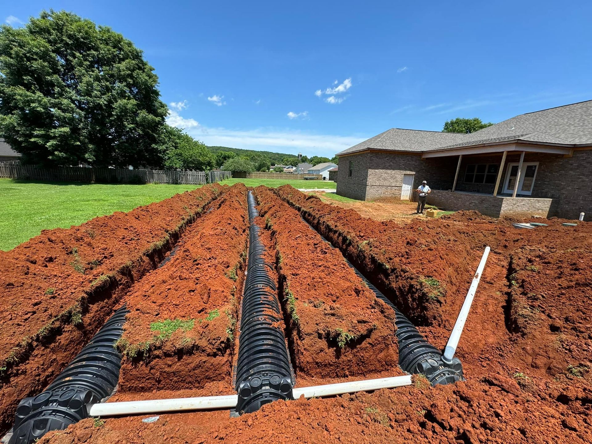 A septic system is being installed in the dirt in front of a house.